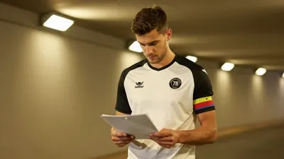 A 25-year-old central defender, tall with a strong build, stands in the dimly lit tunnel of the 711 Stadion, his face set...