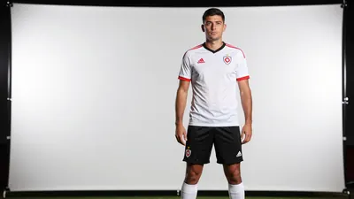A photorealistic image of a 30-year-old male coach with a medium build, wearing a white Telstar jersey with a red stripe...